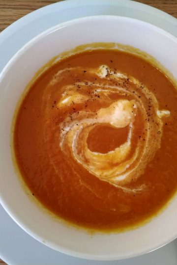 Carrot and sweet potatoe soup served in a bowl with sour cream swirl