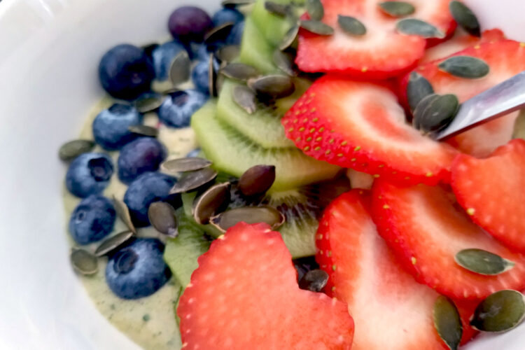 Green smoothie bowl with blueberries, strawberries and kiwis close up
